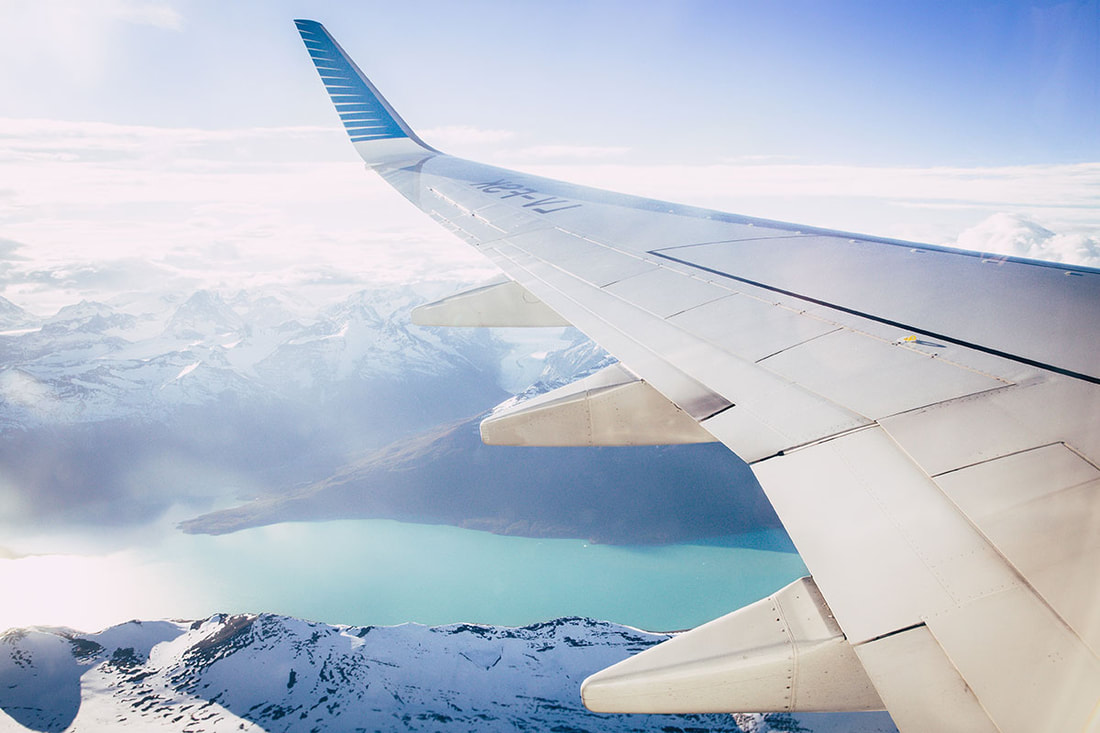 Wing of an airplane and snow-capped mountains