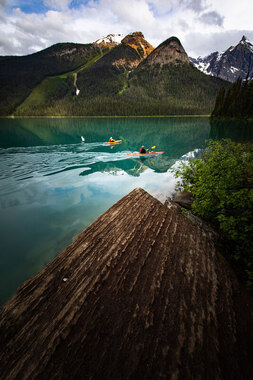 Two people kayaking on a lake in front of a mountain